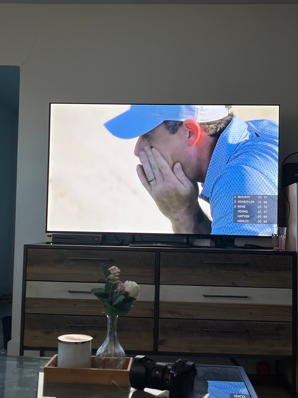 TV showing Rory McIlroy overcome with emotion at the top of the leaderboard